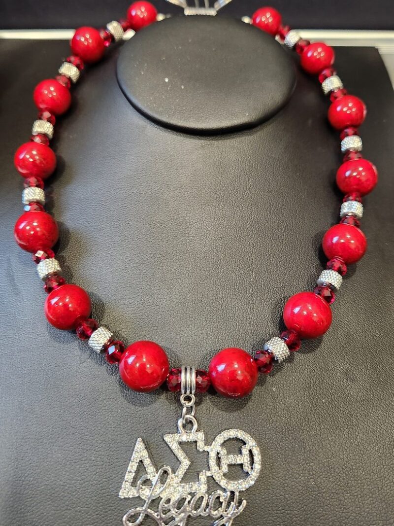 Style D01 – Red coral-tone rounds, faceted red crystal rondelles, textured silver spacers, rhinestone ΔΣΘ Legacy pendant