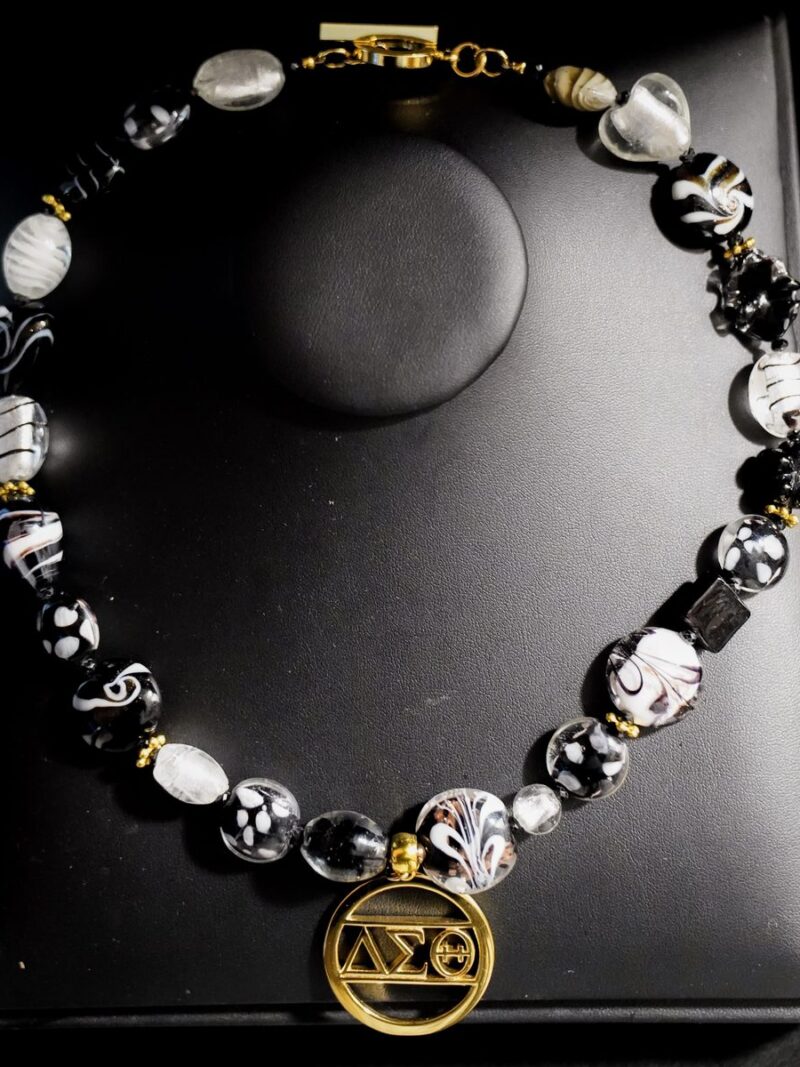 Style D04 – Black, white and clear lampwork/foil glass beads, gold daisy spacers and toggle, gold cut-out ΔΣΘ circle pendant
