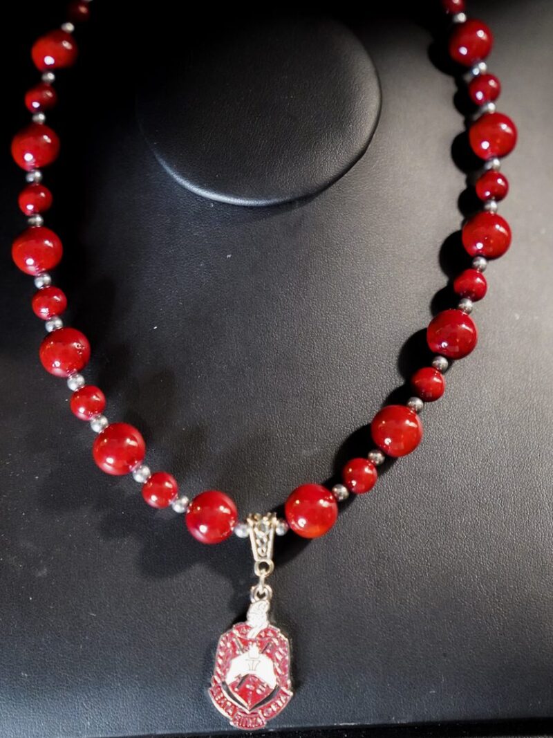 Style D06 – Graduated deep-red rounds with hematite spacers, red enamel Delta Sigma Theta crest pendant