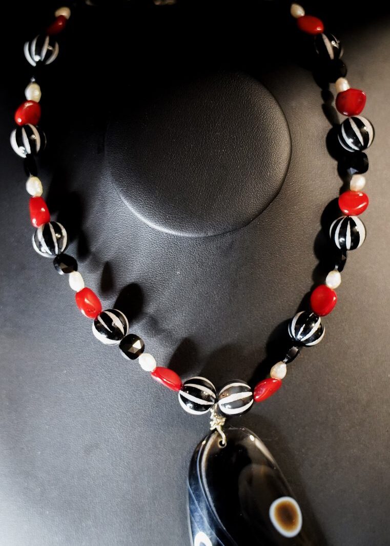 Style N02 – Black/white carved striped beads, red coral, freshwater pearls, faceted onyx, large black eye-agate pendant