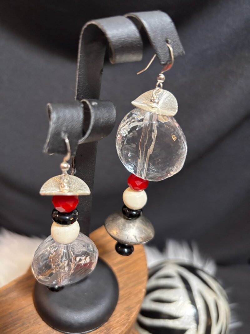 Signature Earrings: clear faceted crystal with red, black and pearl beads and silver caps on a leather display